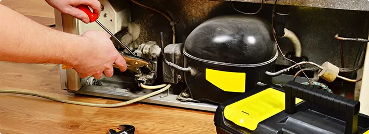 Refrigerator repair technician fixing the compressor and wiring in Nedrow, NY