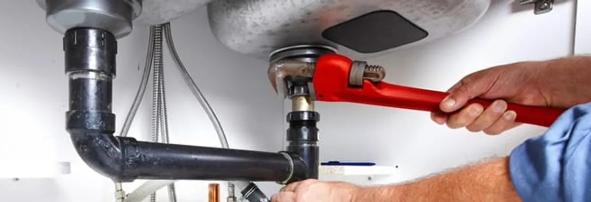 Garbage disposal repair technician tightening the sink drain and disposal connection in Syracuse, NY