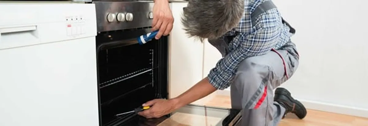 Oven repair technician inspecting and servicing an electric oven in Syracuse, NY